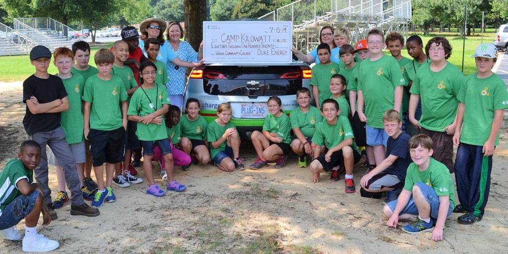 Millie Chalk, a community relations manager for Duke Energy (left side, beside car) presents a donation from Duke Energy Foundation to campers at Wayne Community College’s Camp Kilowatt and two of their leaders, WCC Instructor and Camp Kilowatt Founder Angela Wall and Camp Counselor Julie Heath.
