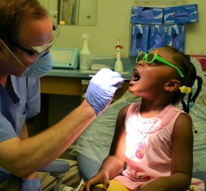 Dr. Kevin Buchholtz checks Sydney Singleton's teeth during a kindergarten screening.