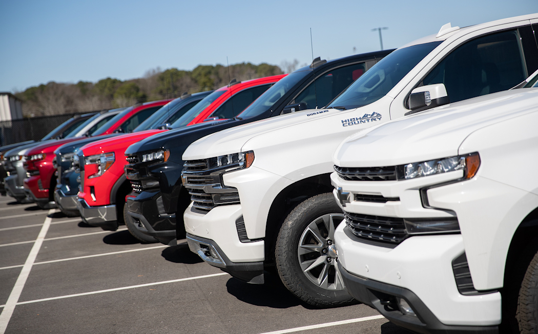 A line of GM trucks sits in the WCC Ash Building parking lot.