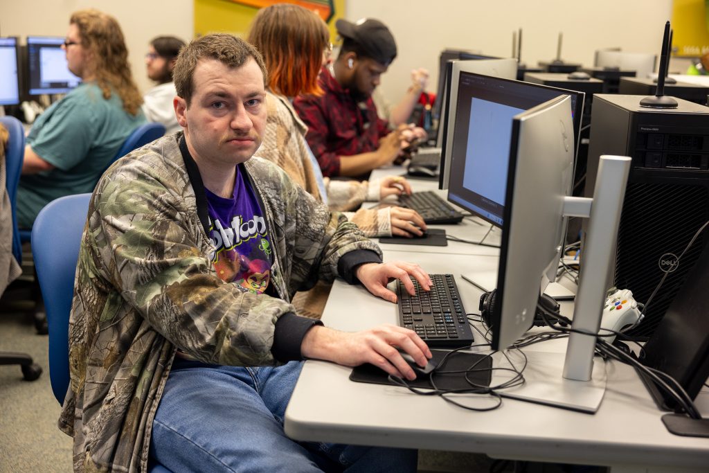 A man sits in front of a desktop computer.