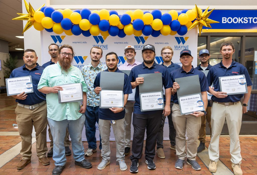 A group of men stand together holding certificates.