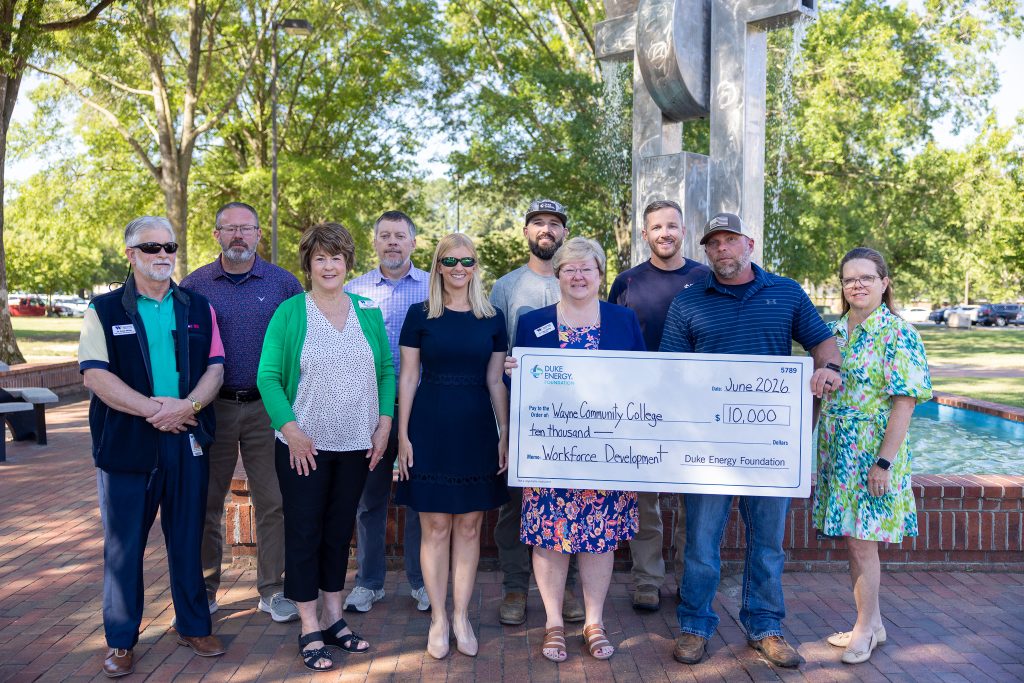Individuals stand outside together with two of them holding a big check.