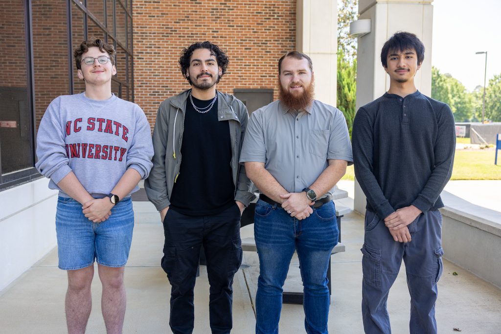Four individuals stand together outside.