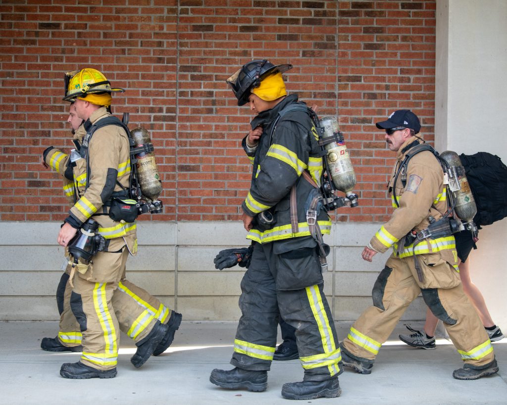 Firefighters walk in uniform.