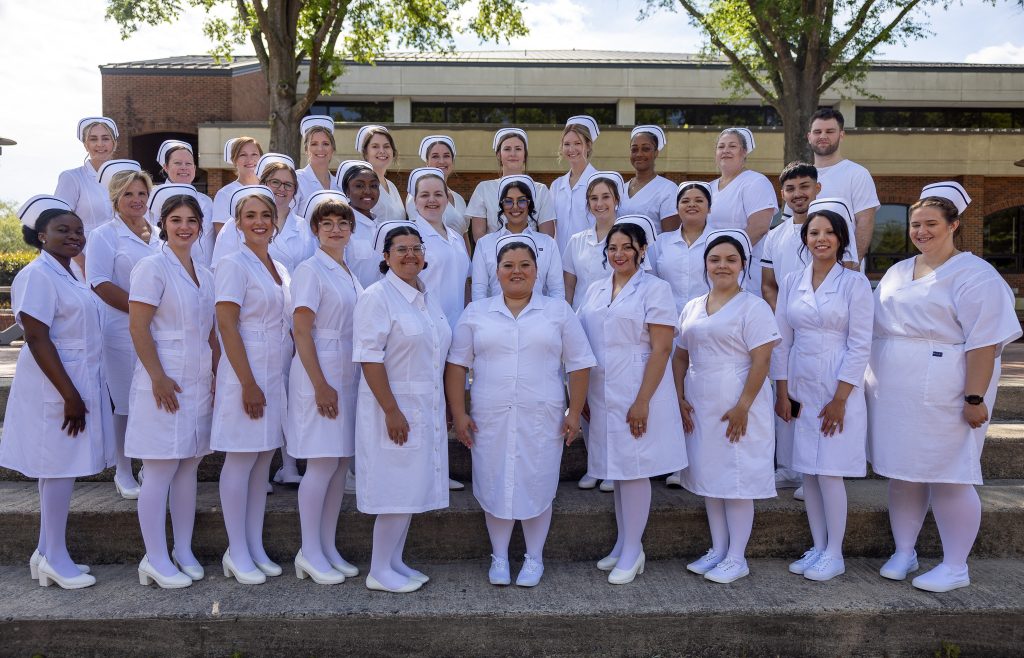 Students wearing traditional nursing uniforms stand together.