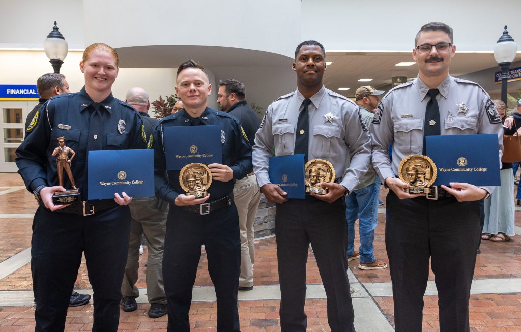 Four individuals stand together holding certificates.