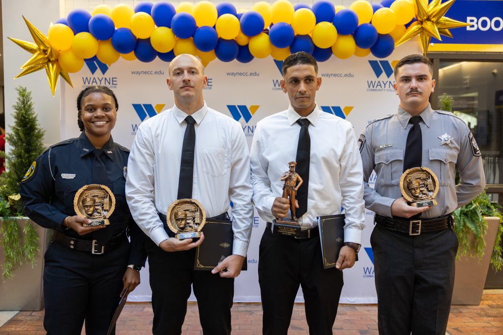 Four individuals stand together holding awards.