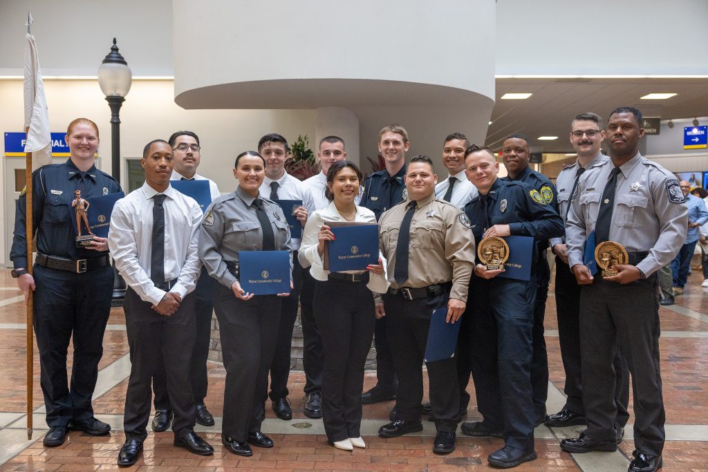 A group of people stand together while holding certificates.