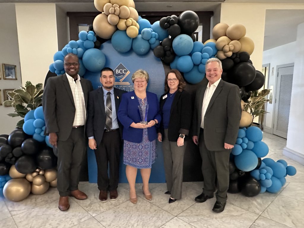 Individuals stand together under a balloon arch.