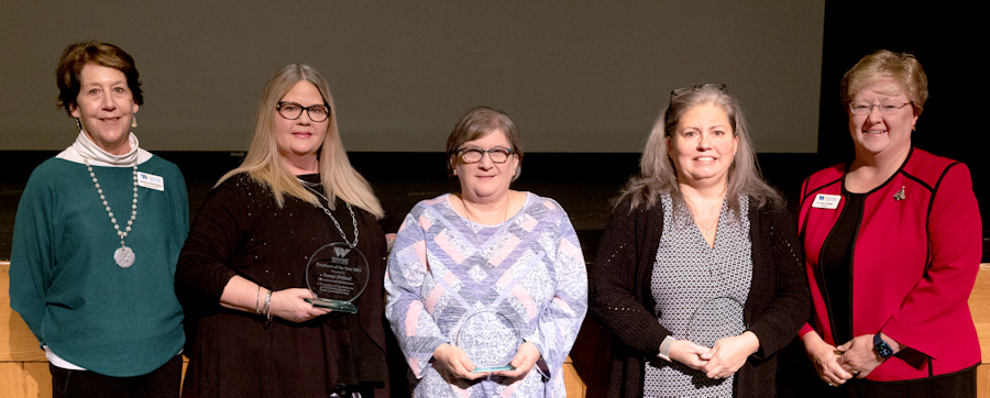 a line of people holding awards