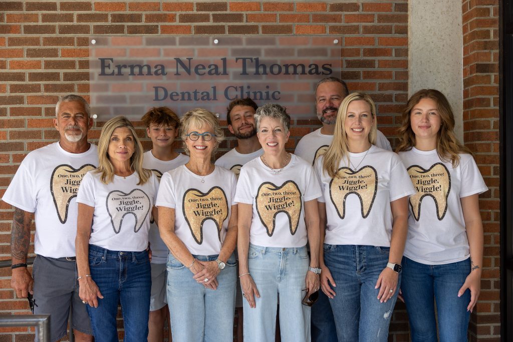 Individuals stand together wearing matching shirts showing a tooth.