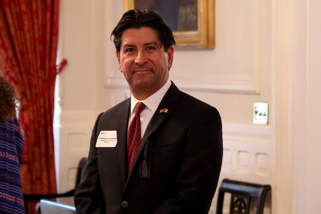 A man wearing a suit and tie stands for a photo.