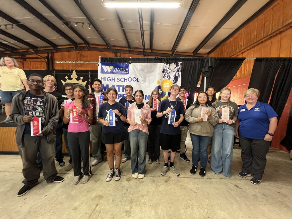 Individuals stand together holding ribbons. 