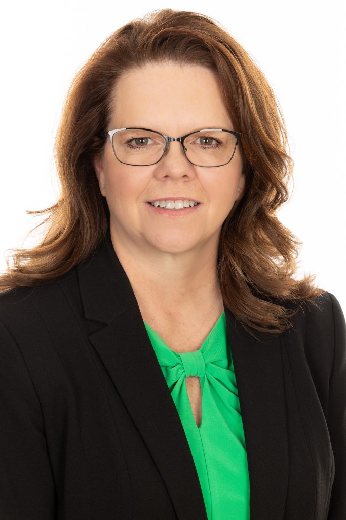 A photo of a woman wearing a green shirt and black blazer.
