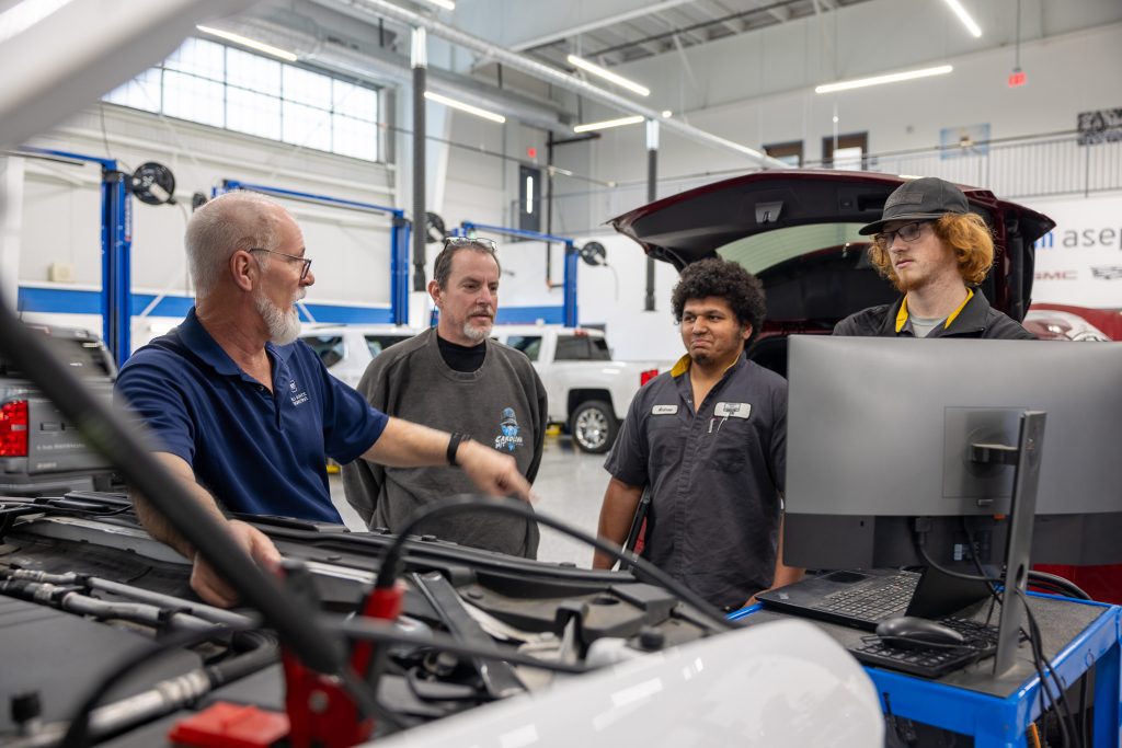 A group stands together in an automotive shop.