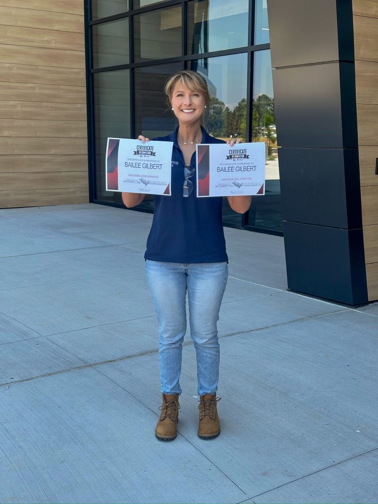 A woman holds two certificates.