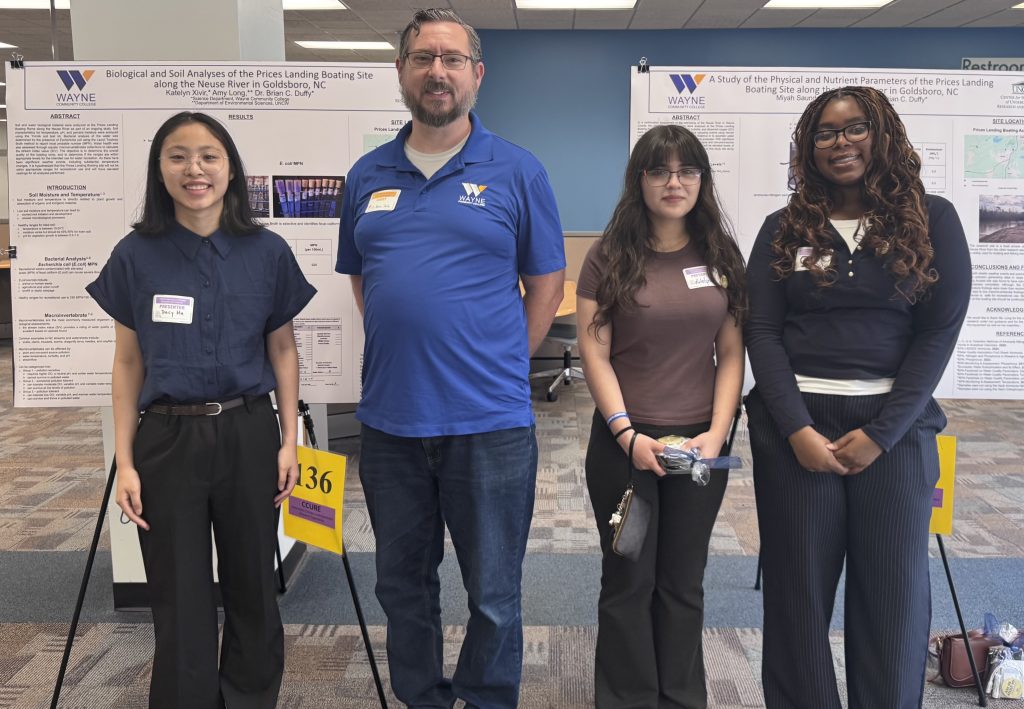 Four individuals stand together in front of posters.
