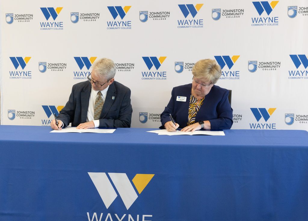 A man and woman sign documents while sitting at a table.