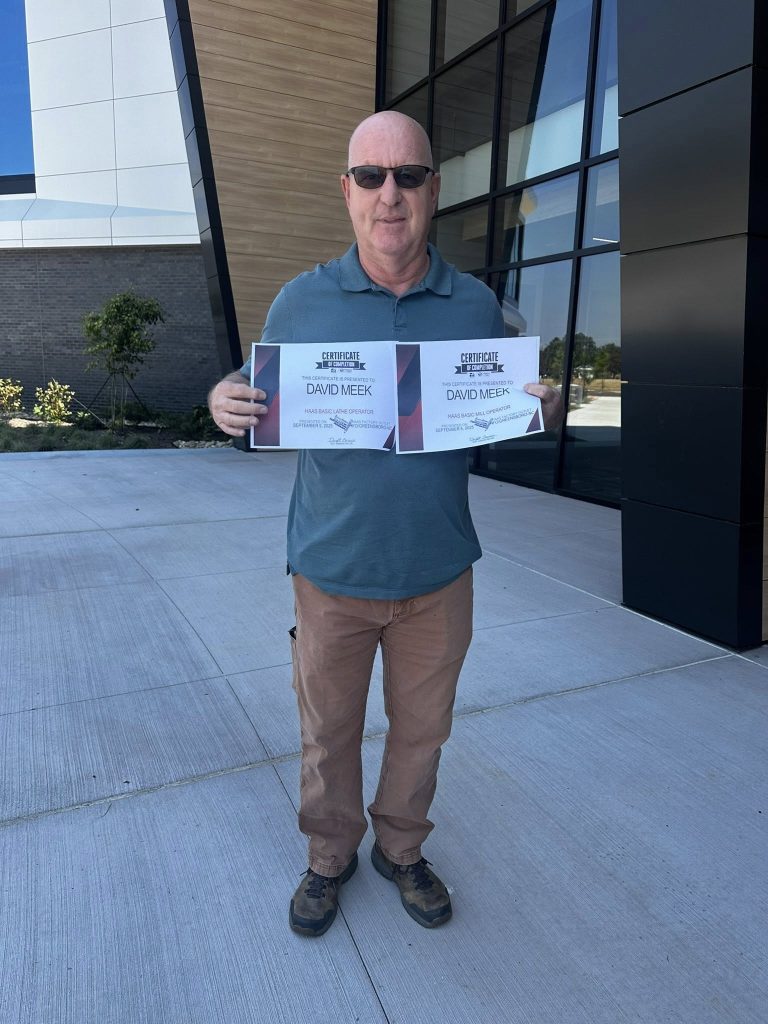 A man stands holding two certificates.