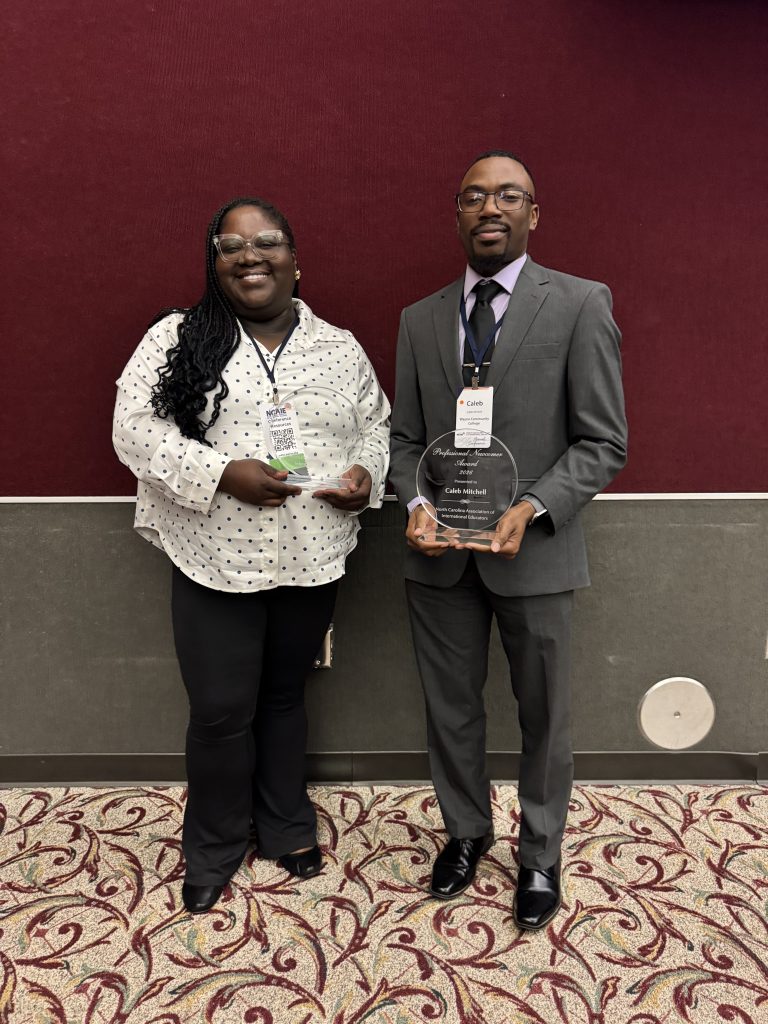 Two individuals stand together holding plaques.