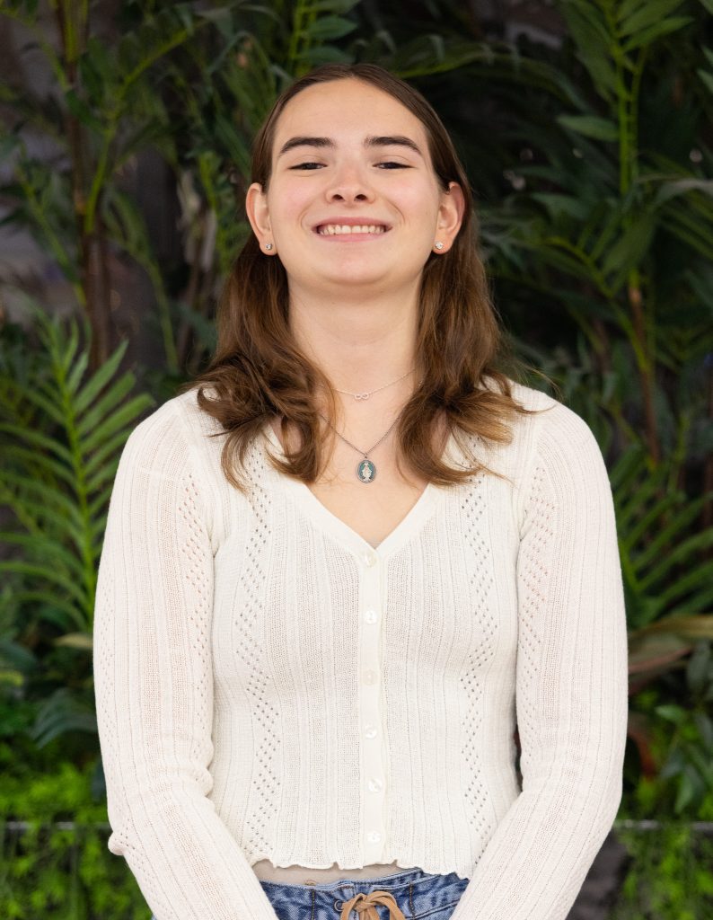 A girl wearing a white top poses for a picture.