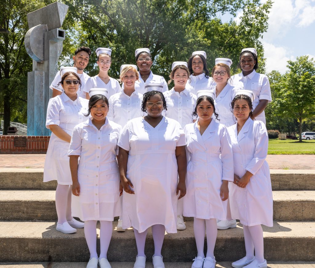 Individuals stand together wearing traditional nursing uniforms.