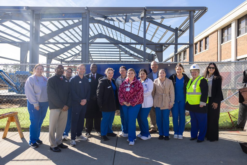 Individuals stand around a steel structure.