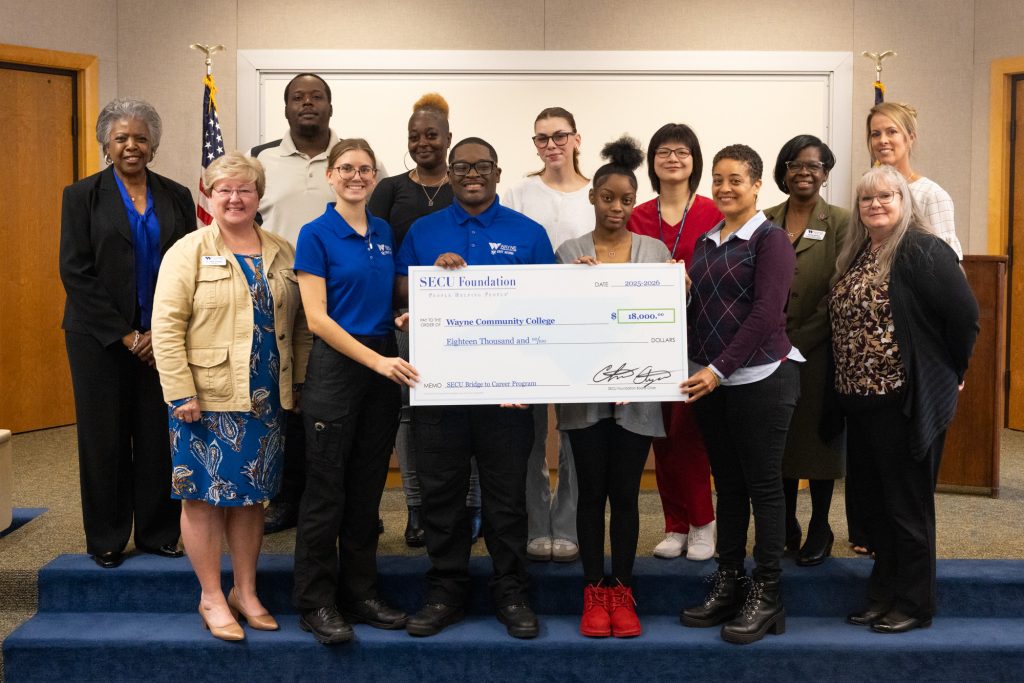 Individuals stand together holding a large check.