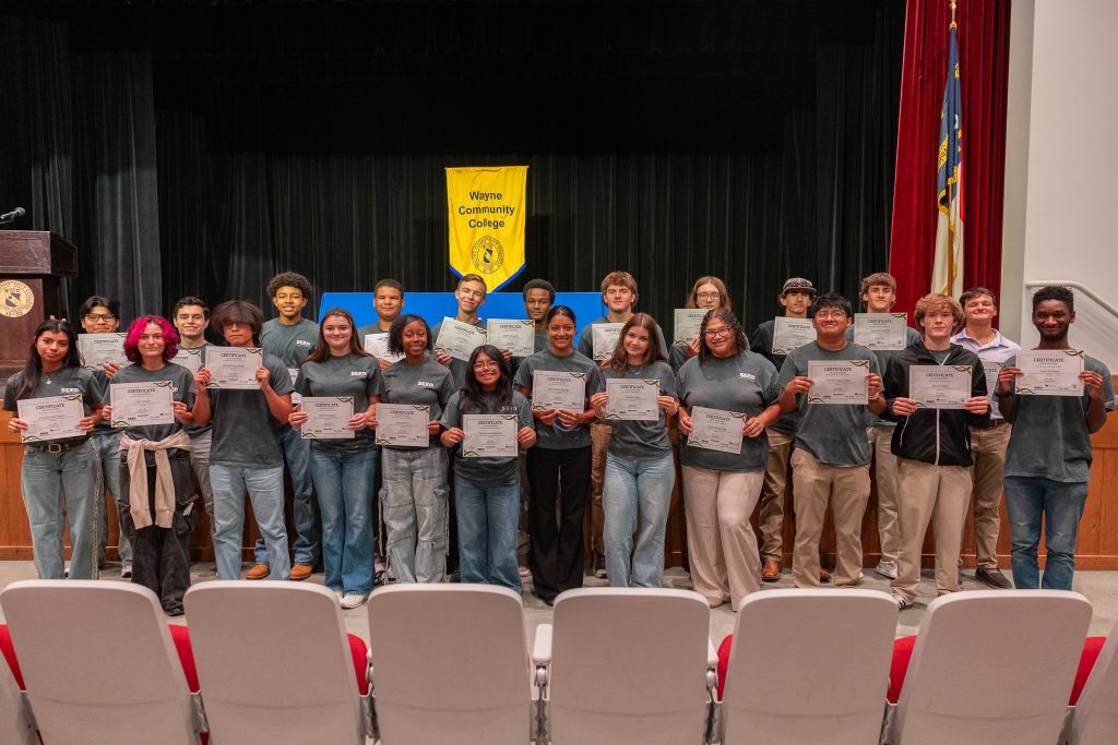Students stand together holding certificates.