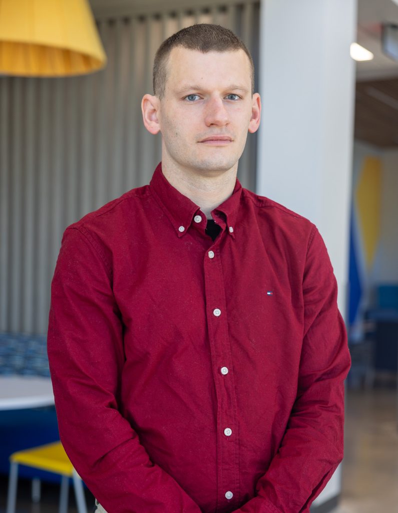 A man stands wearing a red shirt.