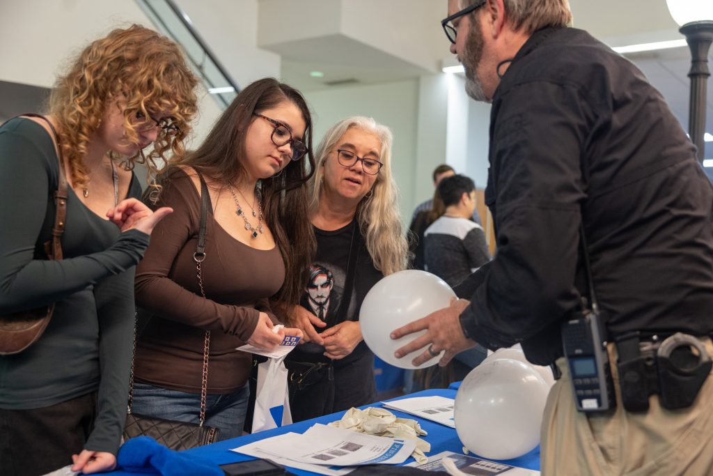 A police offer shows a white balloon to three women.