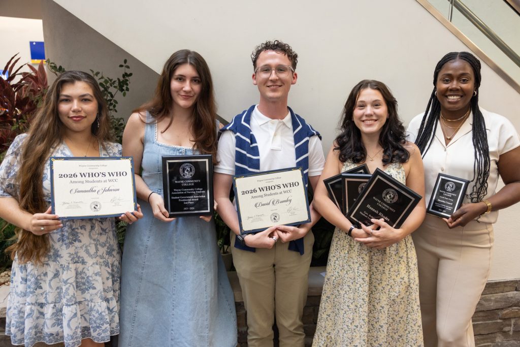 Individuals stand together holding certificates and plaques.