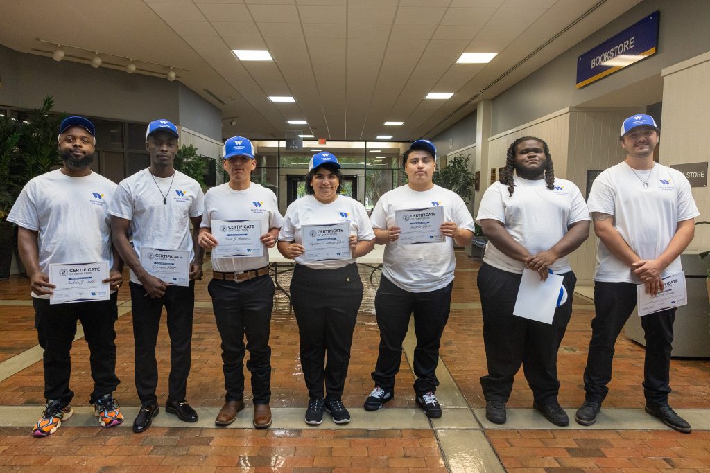 Students stand together holding certificates.