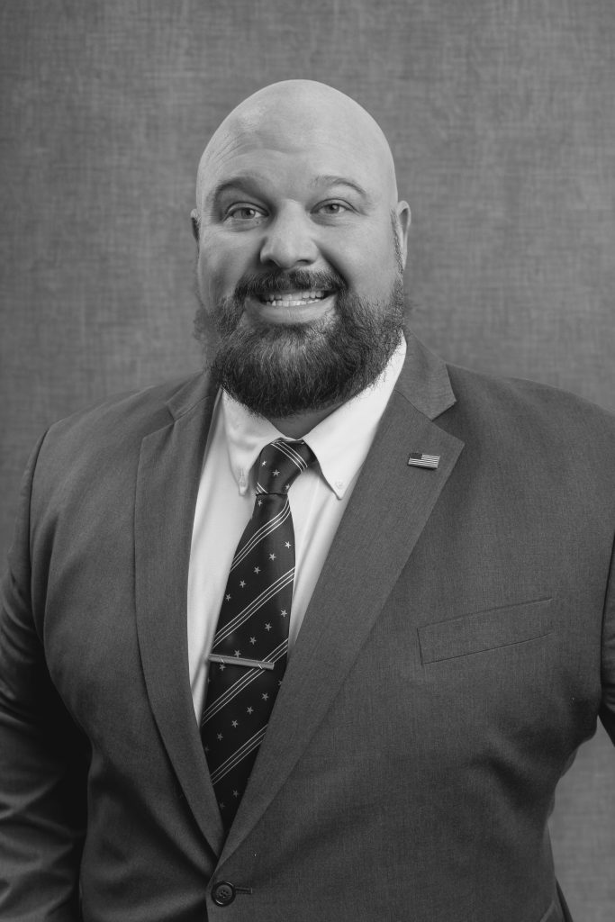 A man is pictured wearing a suit and tie.