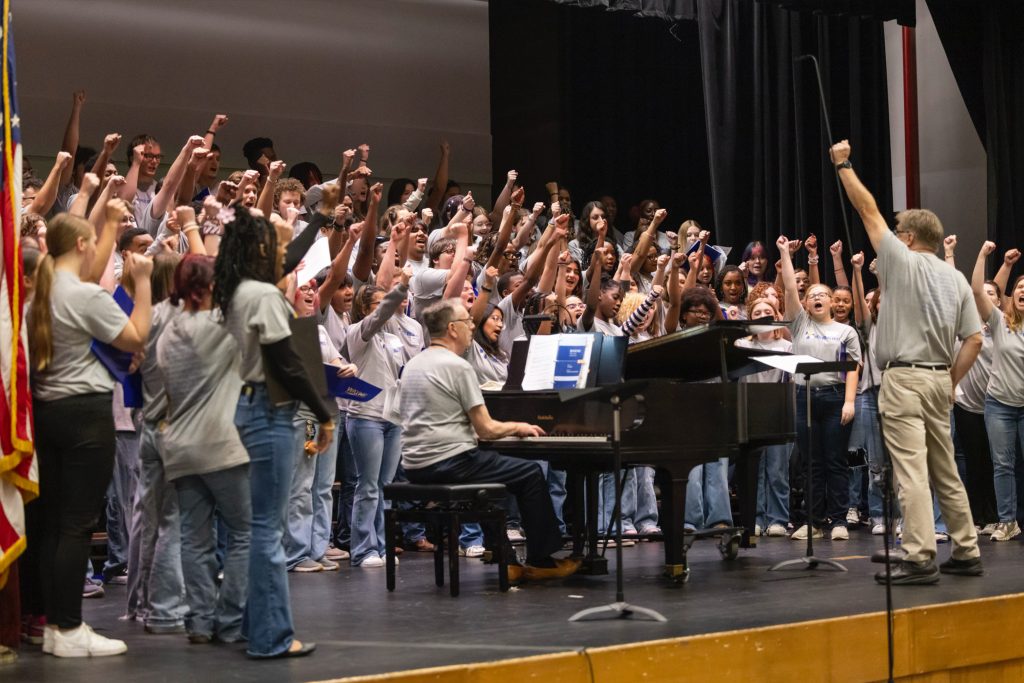 A group of individuals stand on a stage with fists raised.