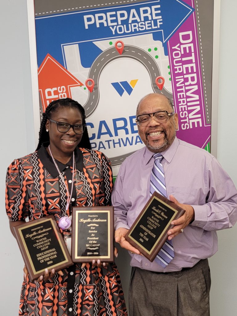 A man and woman stand together holding plaques.