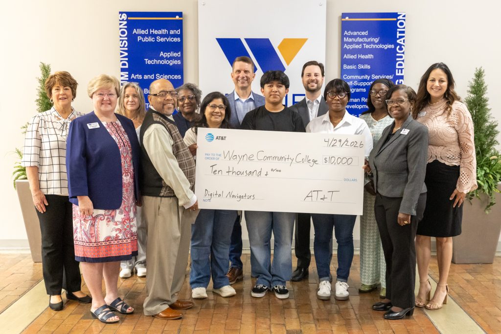A group of individuals stand together holding a big check.