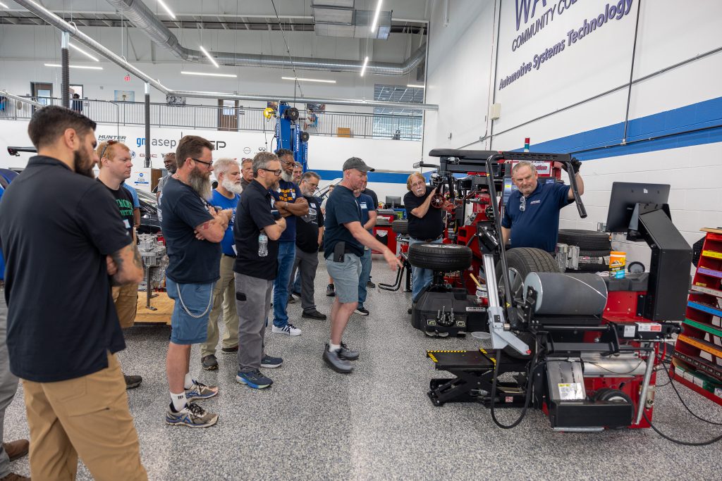 A group of men stand around equipment in a shop.