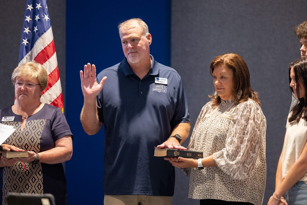 A man raises his hand and has his other hand placed on a Bible, which is being held by a woman.