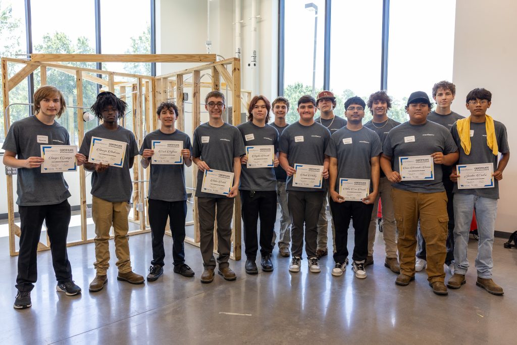 Students stand together holding certificates.