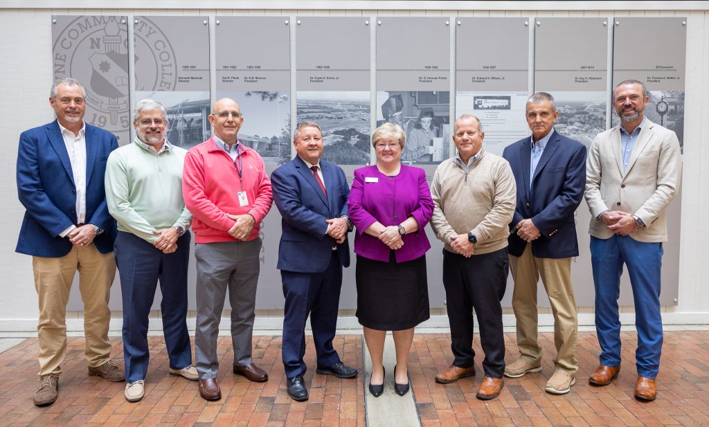 Eight individuals stand together.