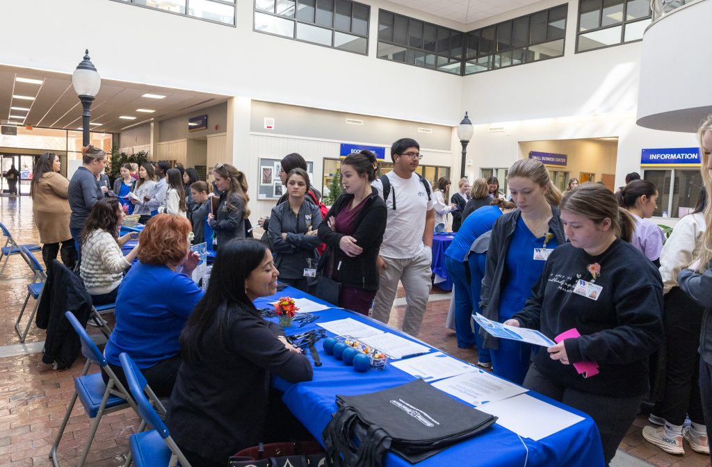 Individuals stand around a table where others are sitting.