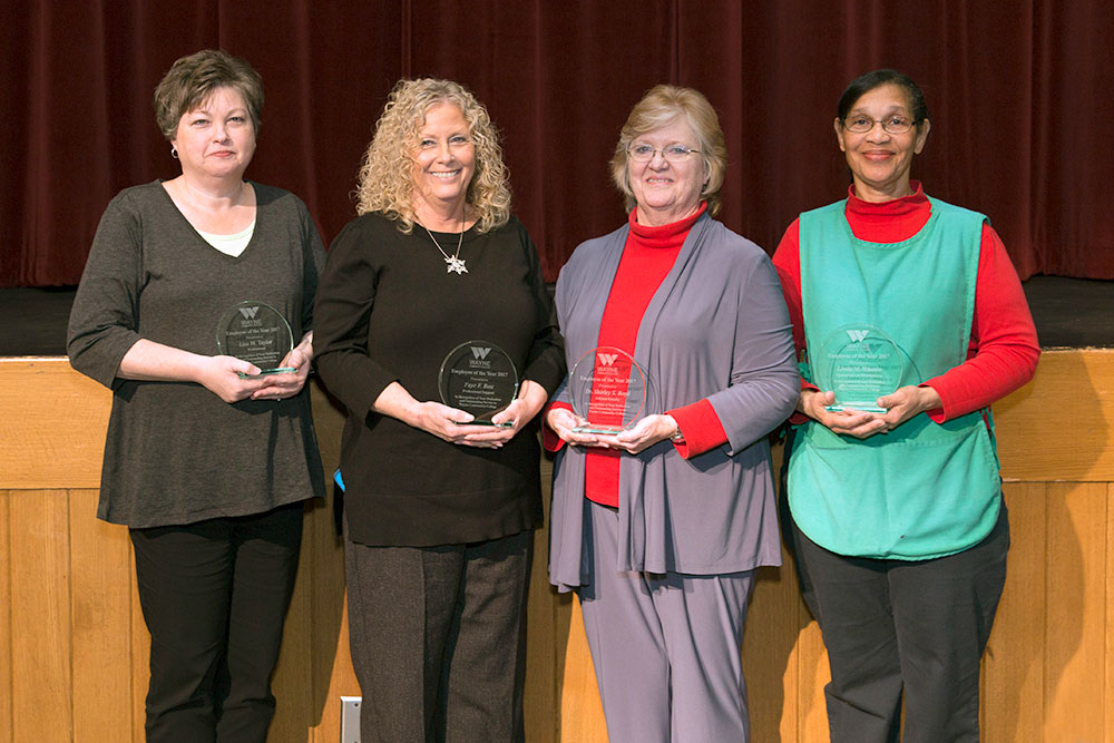 The college's top employees standing with their plaques: 