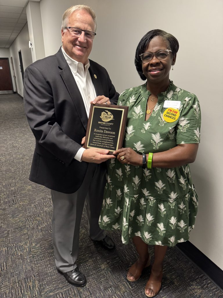 A man and woman stand together holding an award.