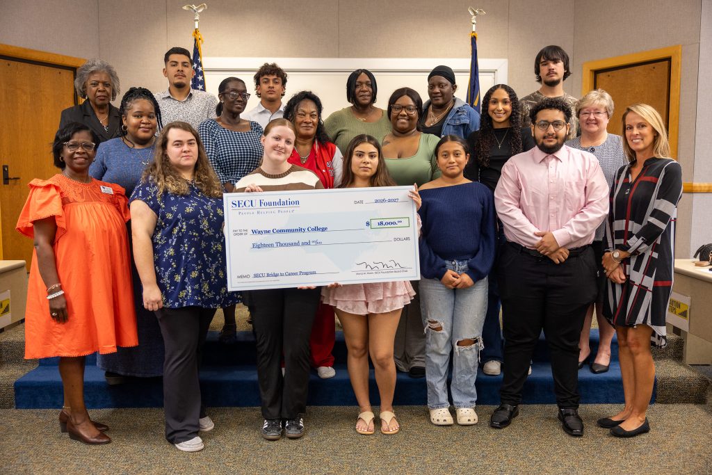 Individuals stand together holding a big check.