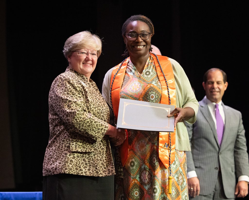 A woman holds a certificate while standing between a man and woman.