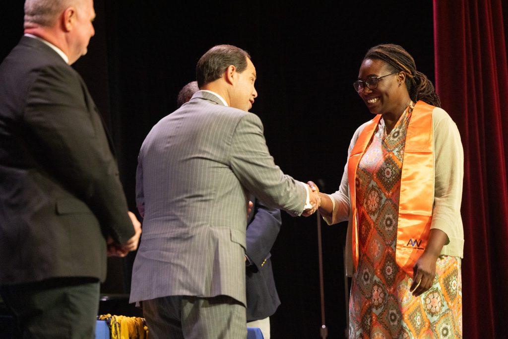 A man shakes a woman's hand while another man stands beside them.